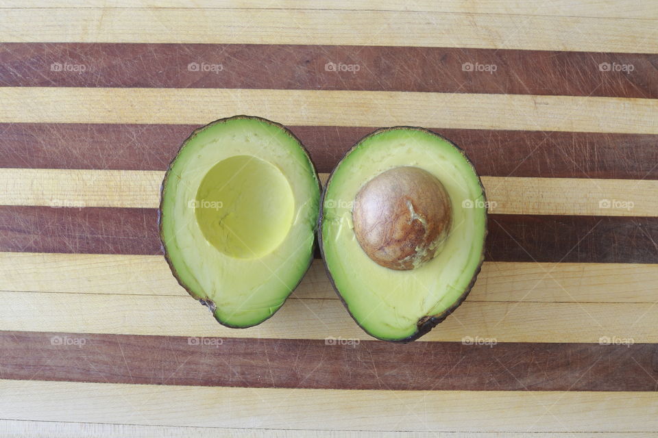 An avocado split in half on a cutting board for a healthy snack. 