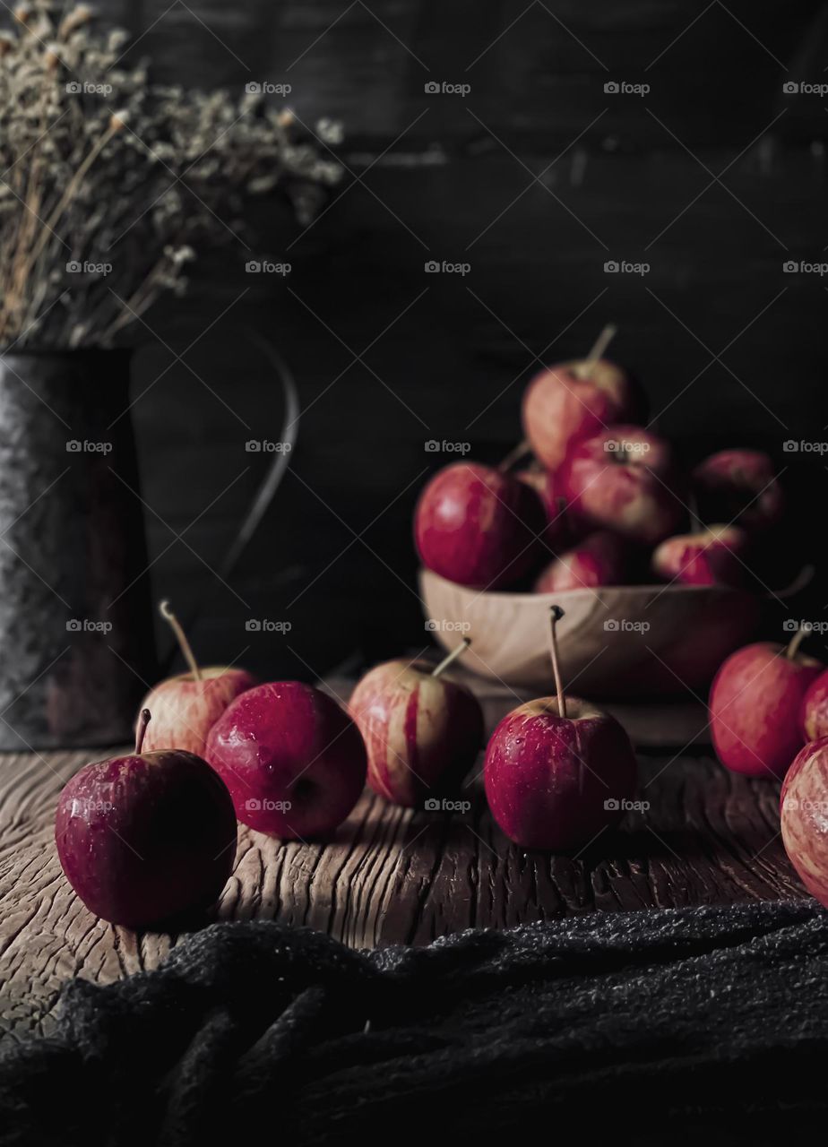 Several Red apples in rustic mood on top of wooden table and some in a wooden bowl