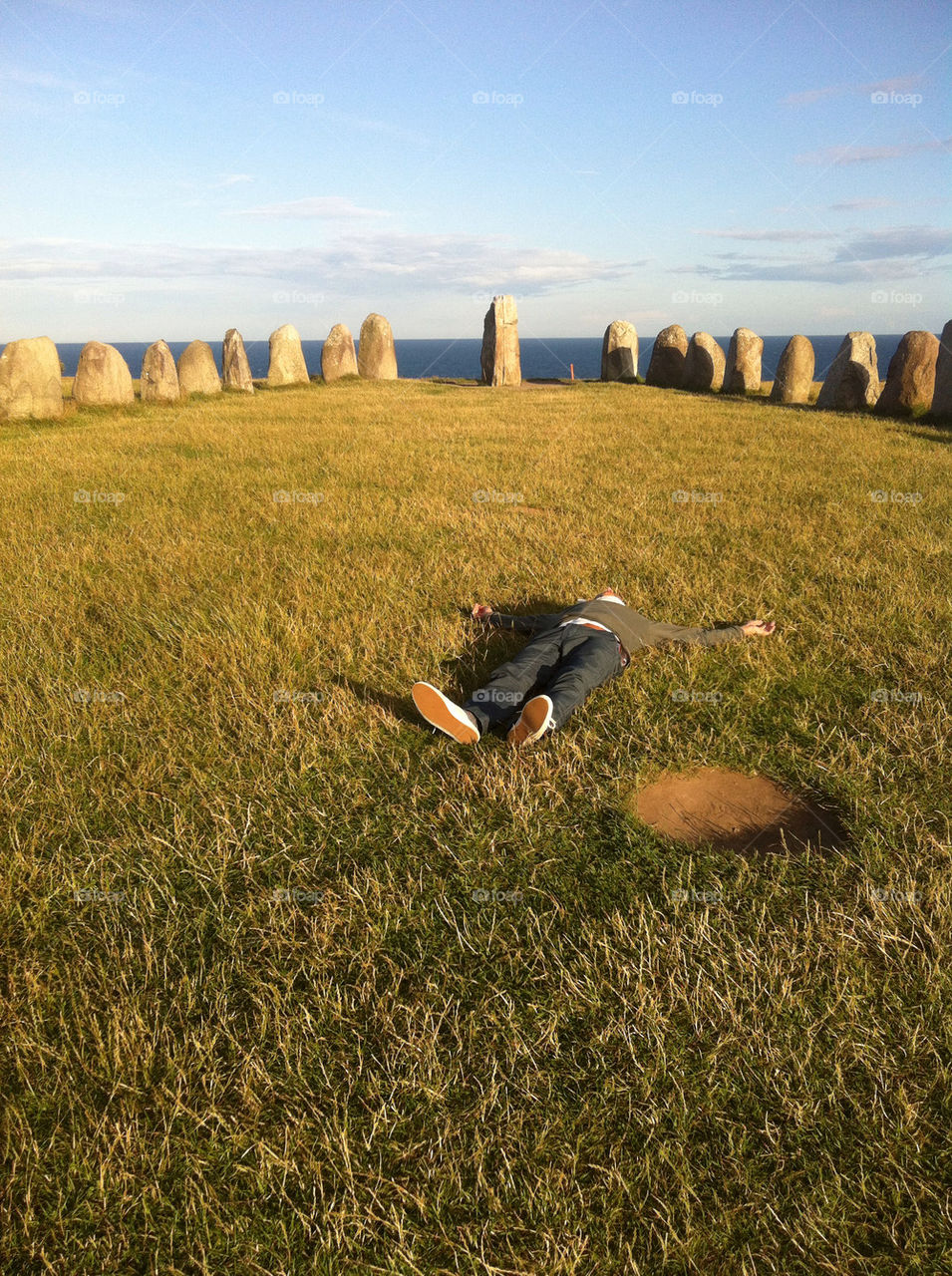 A man laying on the ground at Ale's stones.