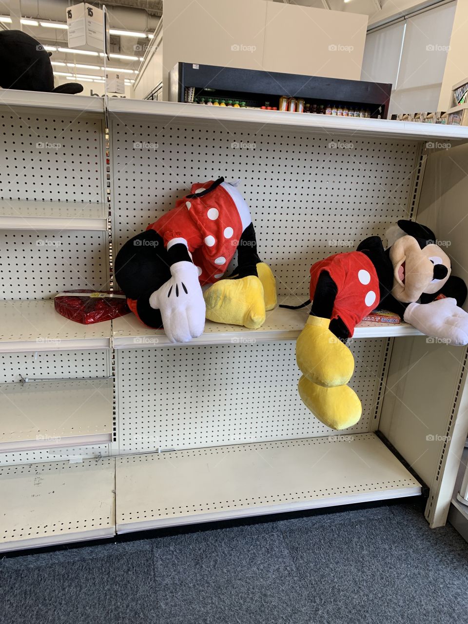 Mickey and Minnie Mouse plush toys sadly slumped on empty shelves. 