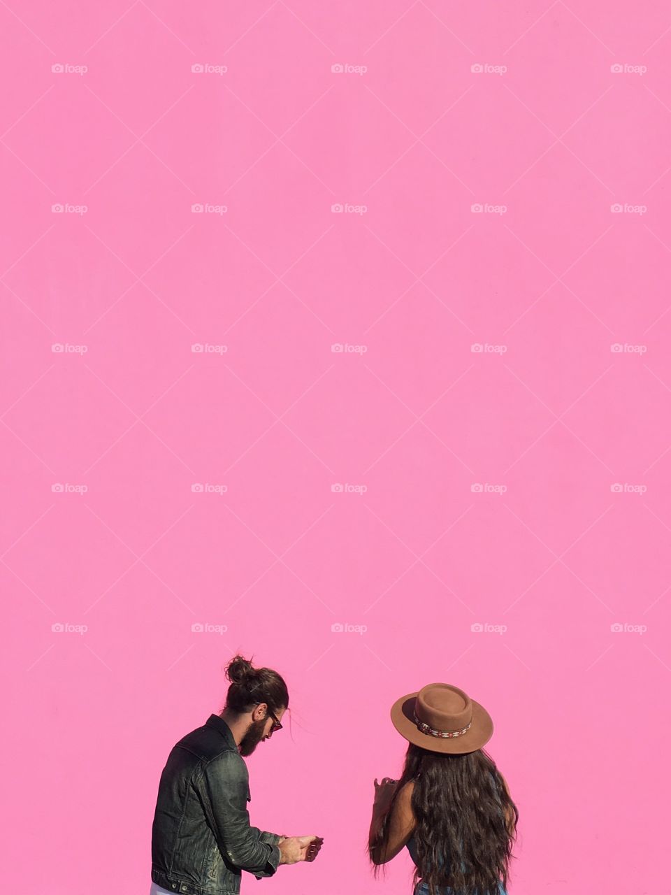 Two people and a pink wall.