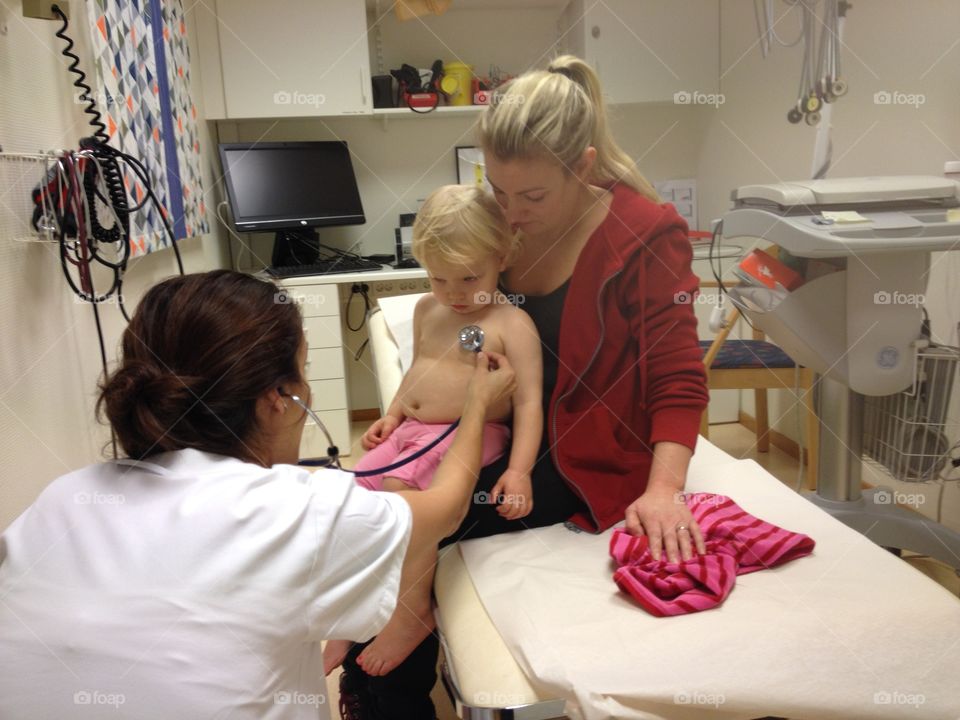 Doctor examining child sitting on his mom's lap