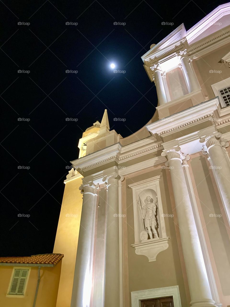 The Basilica of Saint Michael Archangel Basilique Saint-Michel Archange de Menton, France with the full moon over its shoulder.