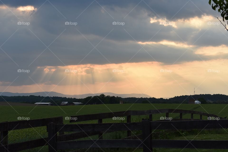 Sunlight shining through clouds over Virginia farmland 