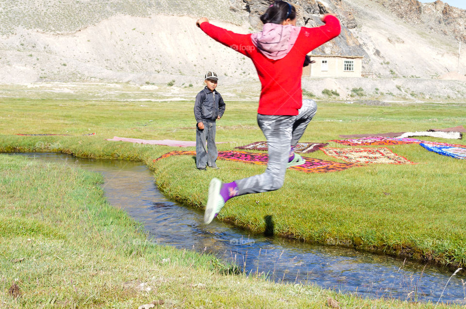 Girl jumping over a stream