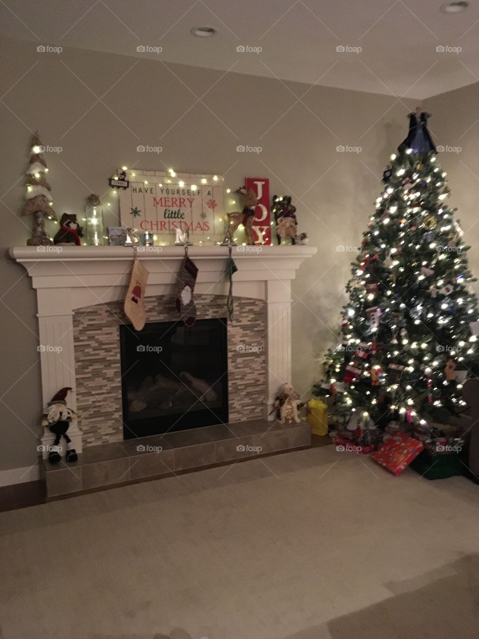 Christmas tree, stockings and fireplace decorated with lights