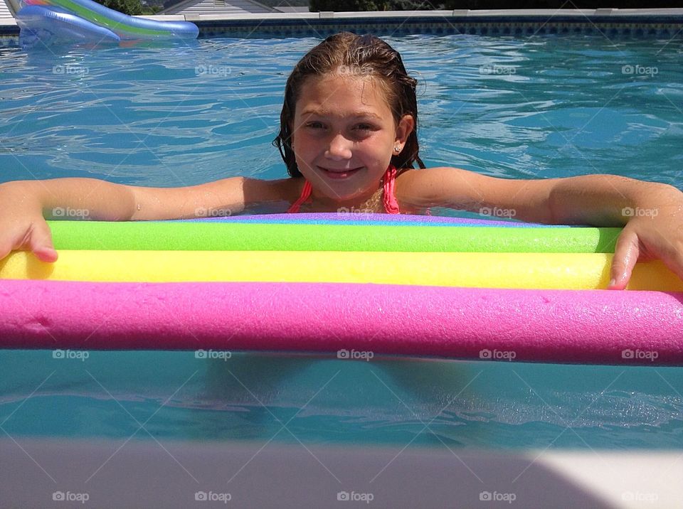 Pretty girl floating with colorful pool noodles. 