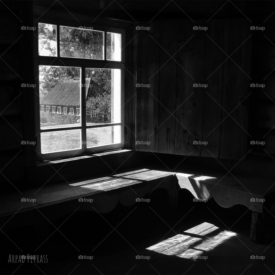 Black and white photo of light coming through a window in an old schoolhouse room