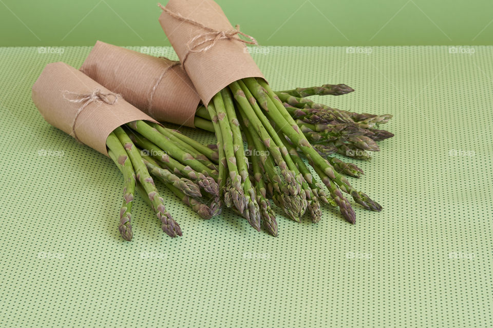 Bunches of fresh asparagus on a green surface 