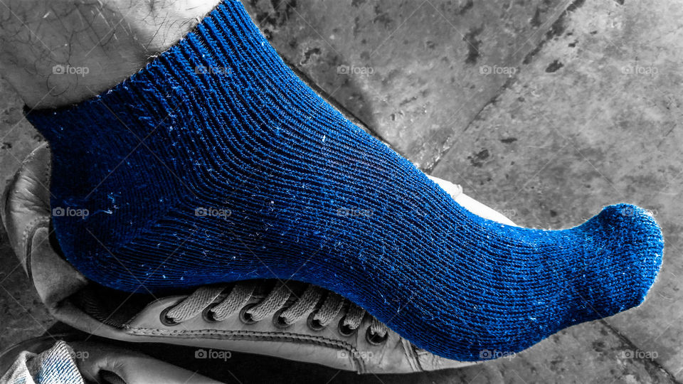 Pé com meia azul escuro.