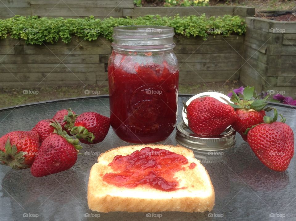 Homemade strawberry jam in a jar with a slice of toast