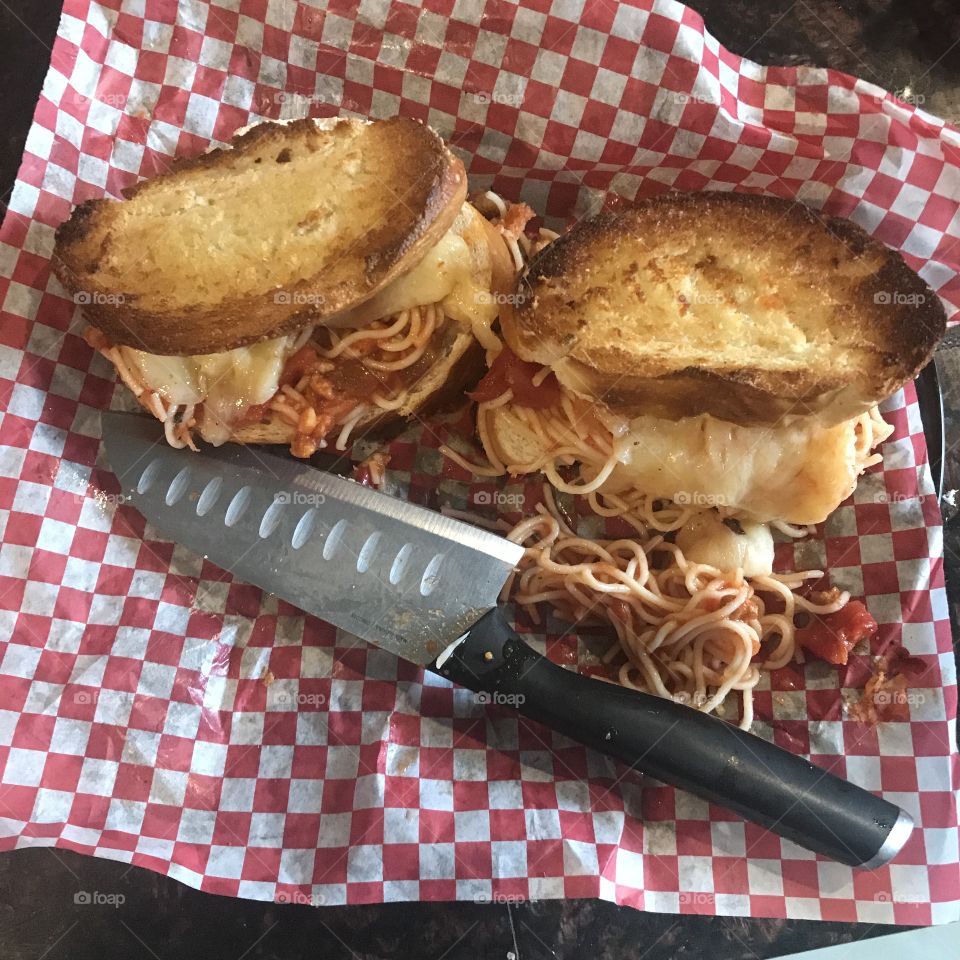Spaghetti and mozzarella cheese sandwiches served on a red and white checkered background 