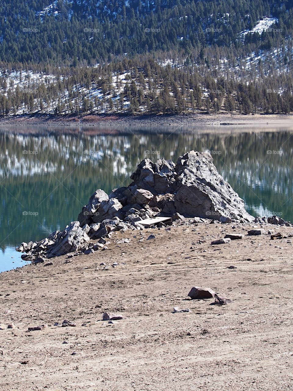 Jagged rocks and boulders along the shoreline of Ochoco Lake in Central Oregon on a sunny spring day.