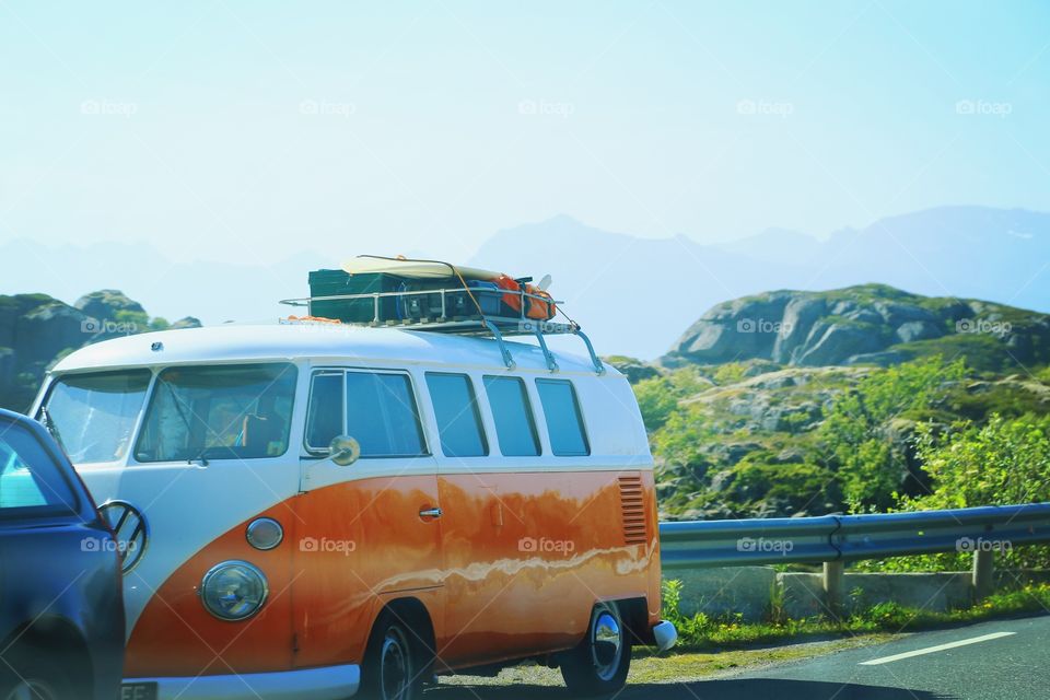 Volkswagen bus on vacation . Driving around in a orange Volkswagen bus with luggage on the roof