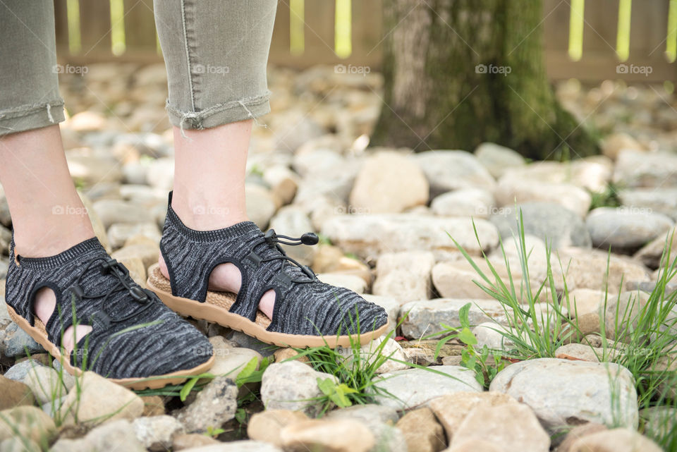 Close-up of a pair of women's shoes walking on rocks outdoors
