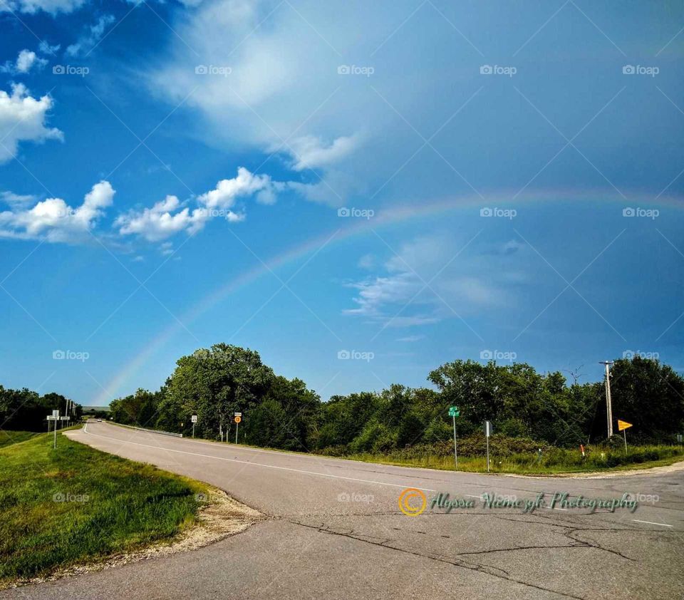Beautiful arched Rainbow over the road "Pot of Gold". Beautiful blue skies.