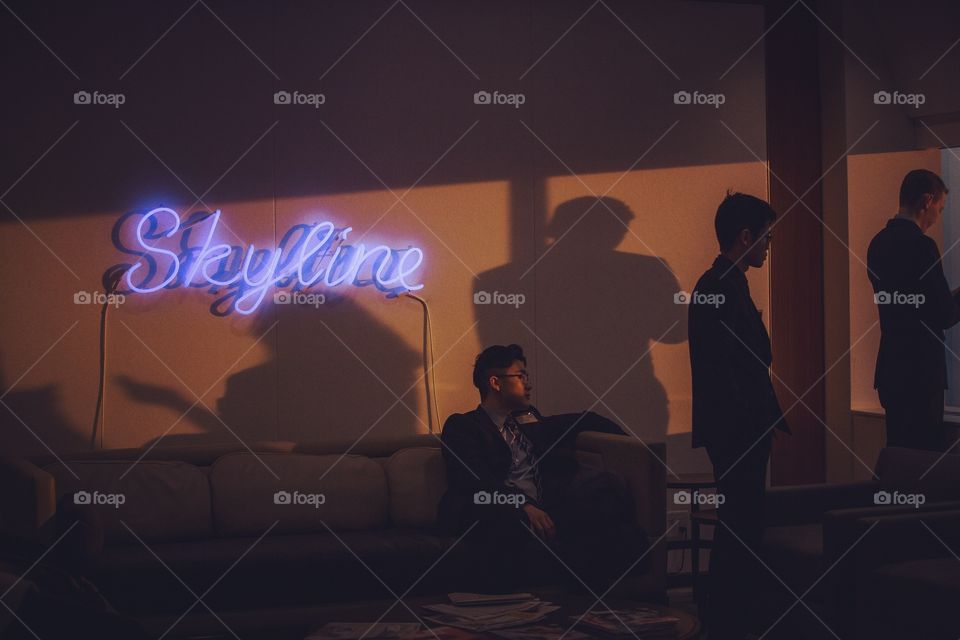 A number of business people taking a break beside a large window at golden hour