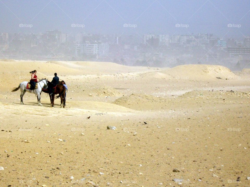 Horseback riders gazing back on the hazy modern city of Cairo 