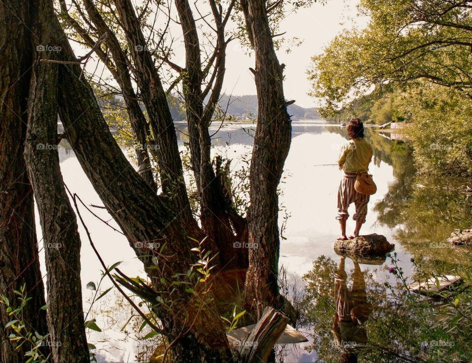 A fisherman at the lake, landscape with trees