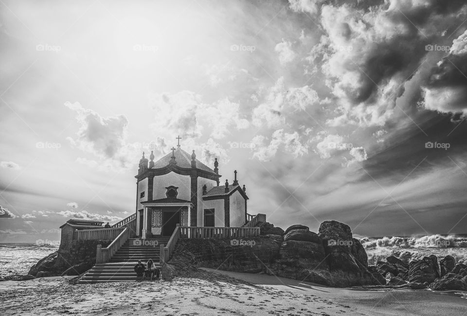 Chapel built on a rock with a epic stormy sky in monochrome