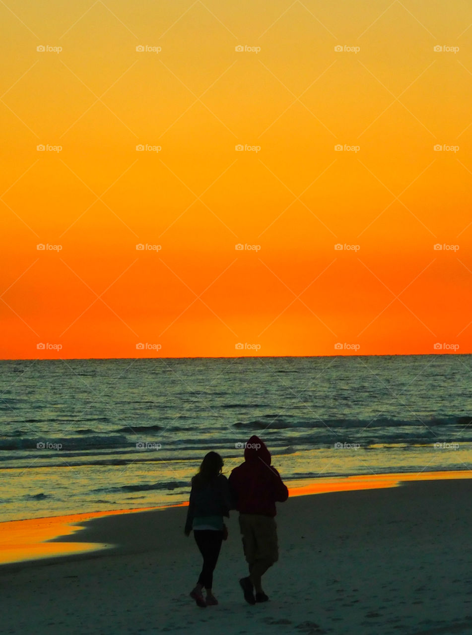A couple enjoys a stroll on the beautiful Gulf of Mexico Sunset!