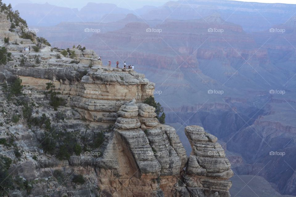 people on the rocks looking at the Grand Canyon