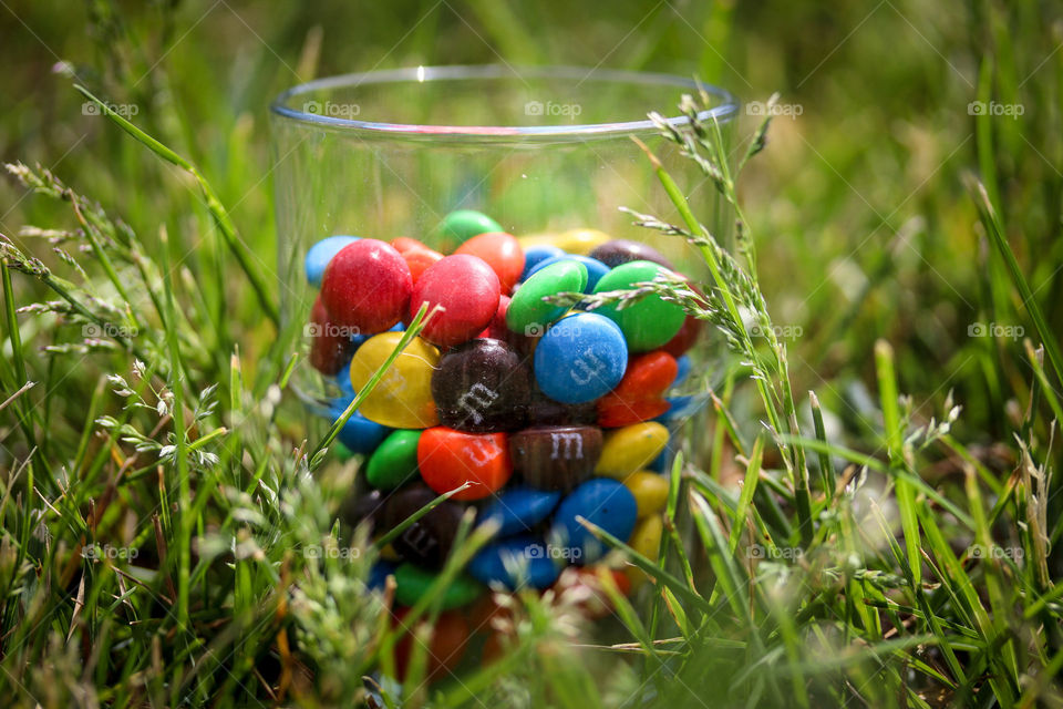 Child is holding glass with M&Ms candies