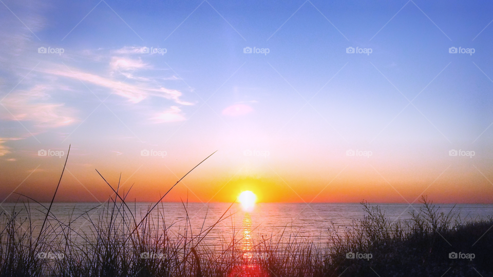 orange sun set on the horizon refecting on lake michigan