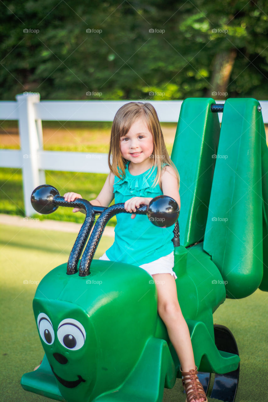 Young Girl on Green Caterpillar at the Playground 