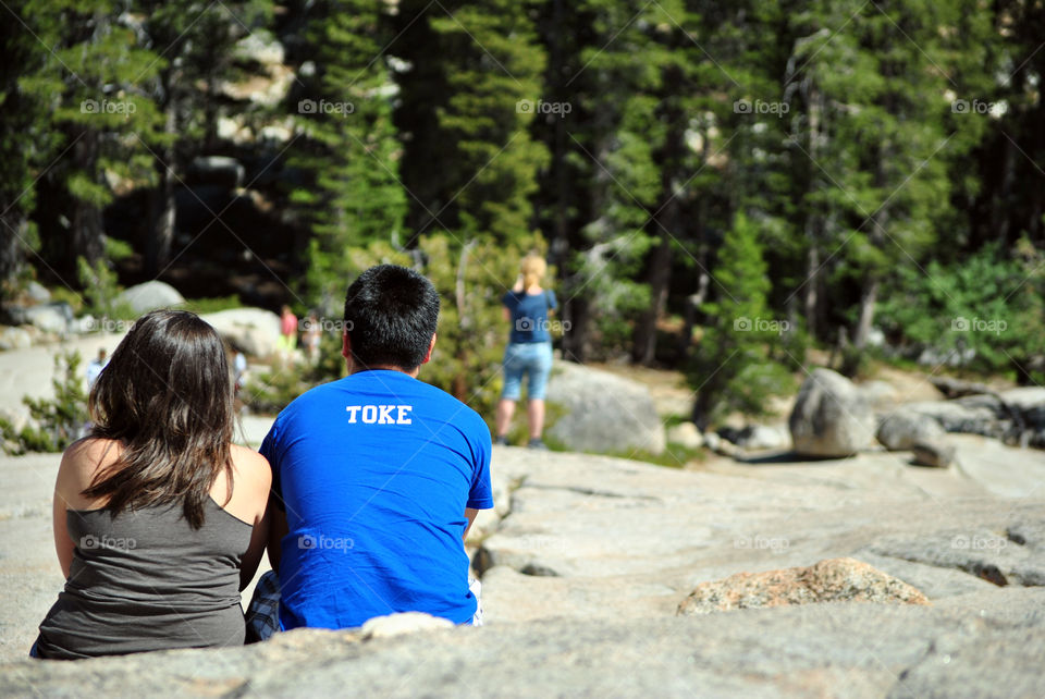 Couple or friends looking at the hiking view, sitting on top of the mountain