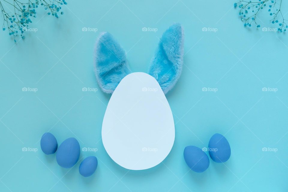 Top view of Easter mockup with blue eggs and bunny ears placed under white egg shaped template