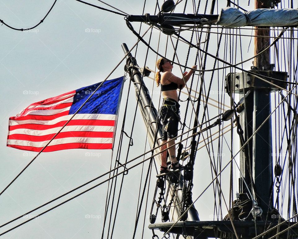 Sailor In The Early Morning. Sailor Climbing The Rigging Of A Tall Ship During The Golden Hour
