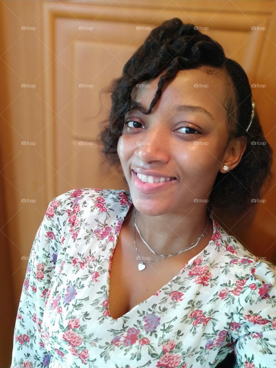 Smiling lady with a curly hair wearing a flower dress