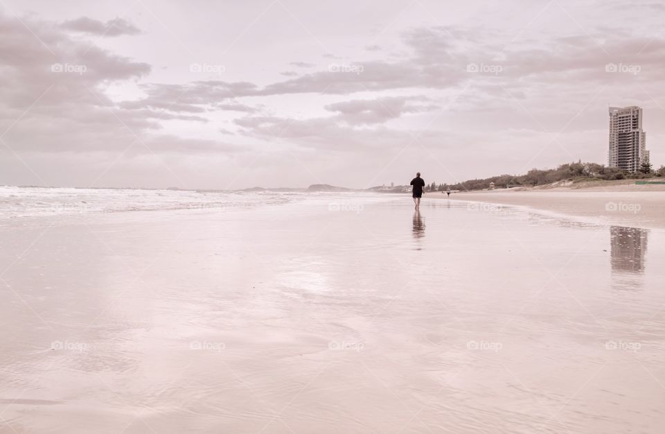 Man walking on the beach at dawn 
