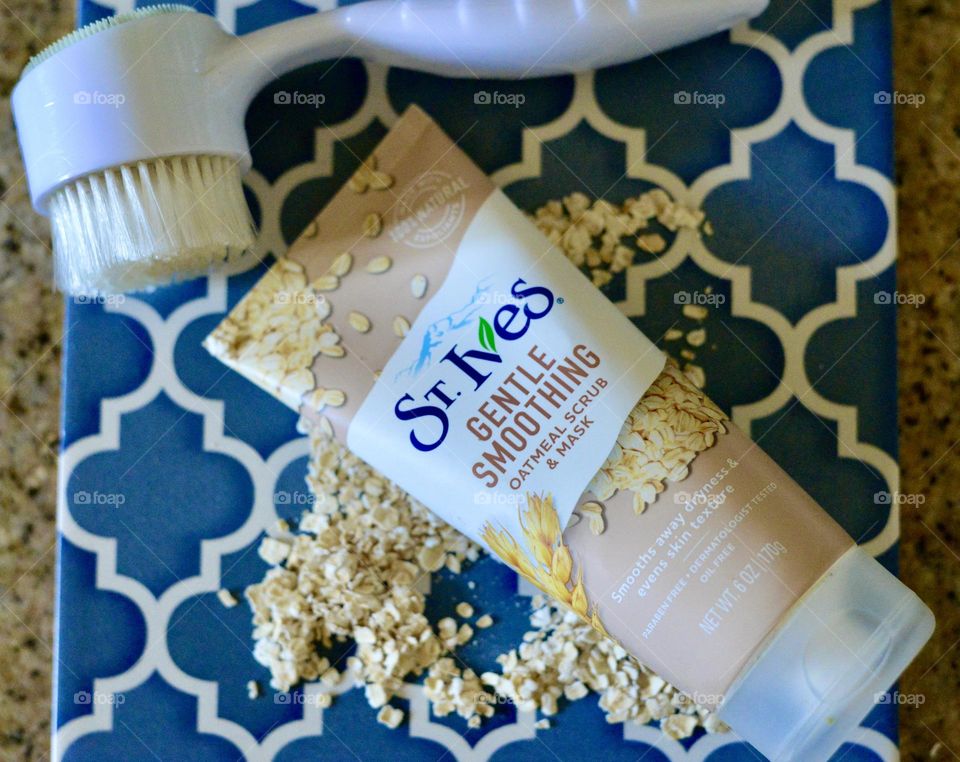 St Ives gentle,smoothing scrub and cleanser with a brush on a blue tile with raw oats