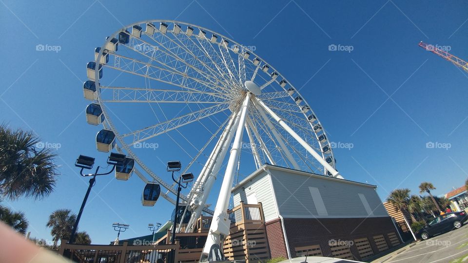large white ferris wheel against clear blue sky at outdoor mall
