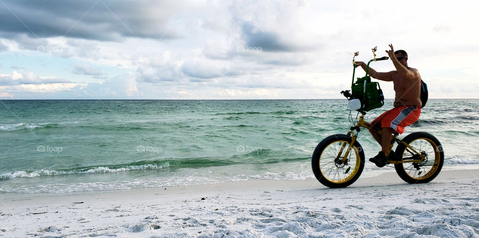 Tourist riding bike on beach.