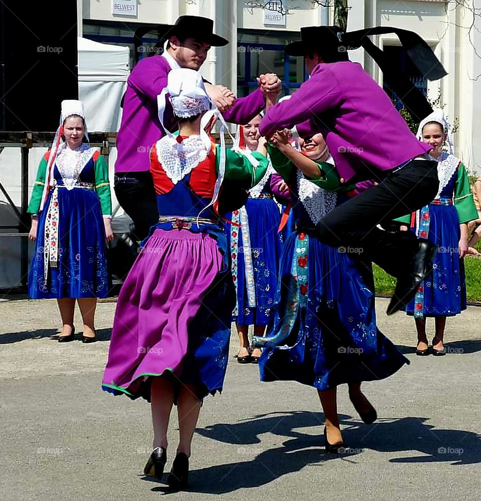 Two women and two men dressed in Breton traditional costumes dancing in a street in Brest at the Printemps des Sonneurs Festival