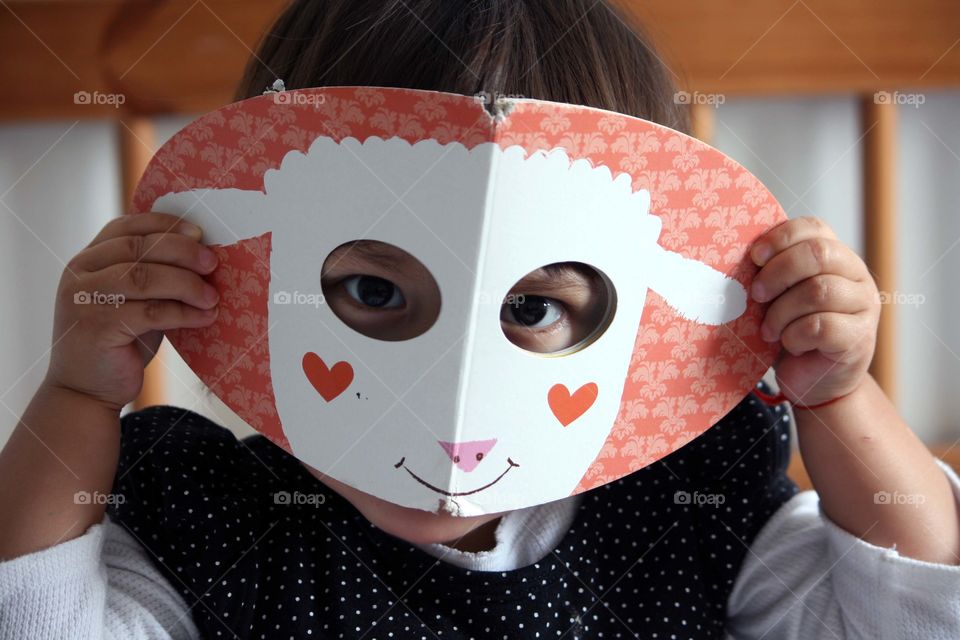 Cute toddler girl looking through holes in book