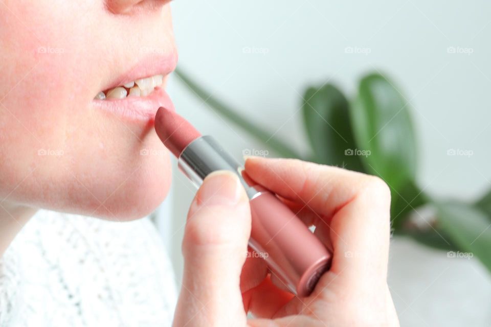 Middle-aged Caucasian woman is putting her lipstick on