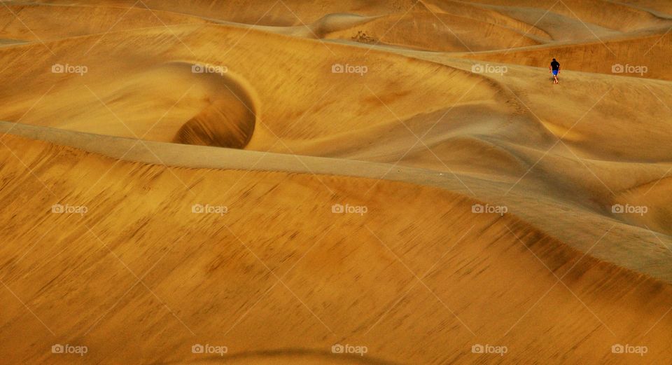 man walking in sandy dunes of maspalomas on gran canaria island in Spain