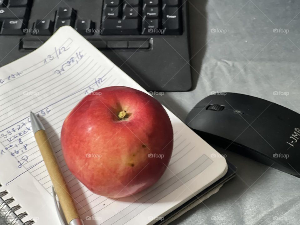 Working desk with notebook, apple and pen 