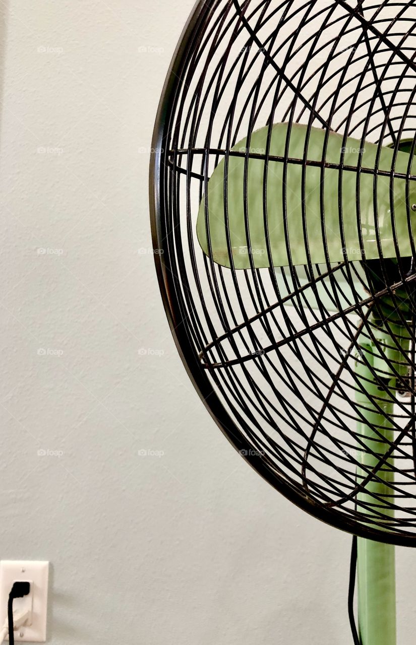 Retro oscillating floor fan plugged into wall outlet 