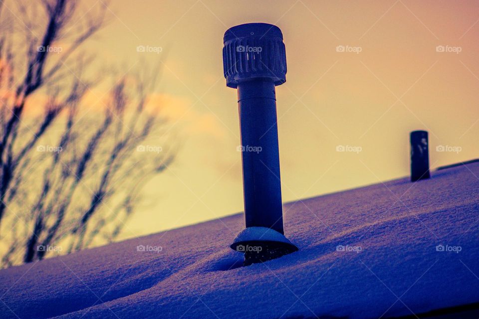 vent in the early morning on a snow covered rooftop