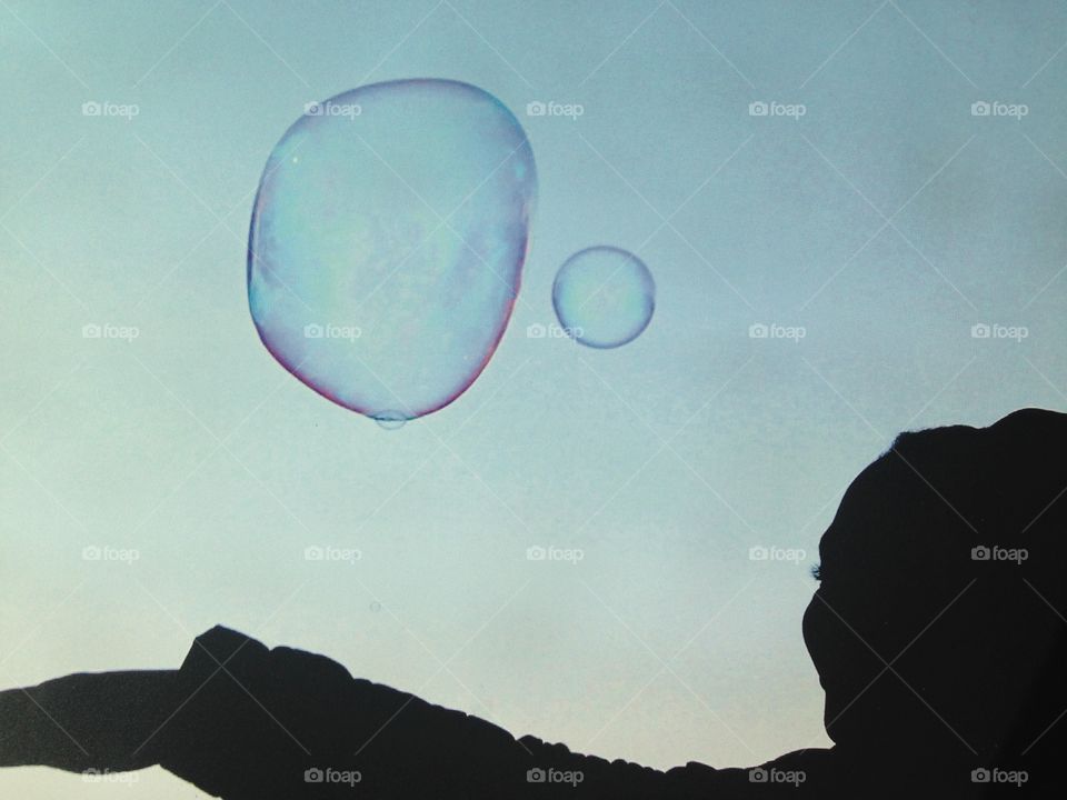 Child silhouette reach for soap bubble in air