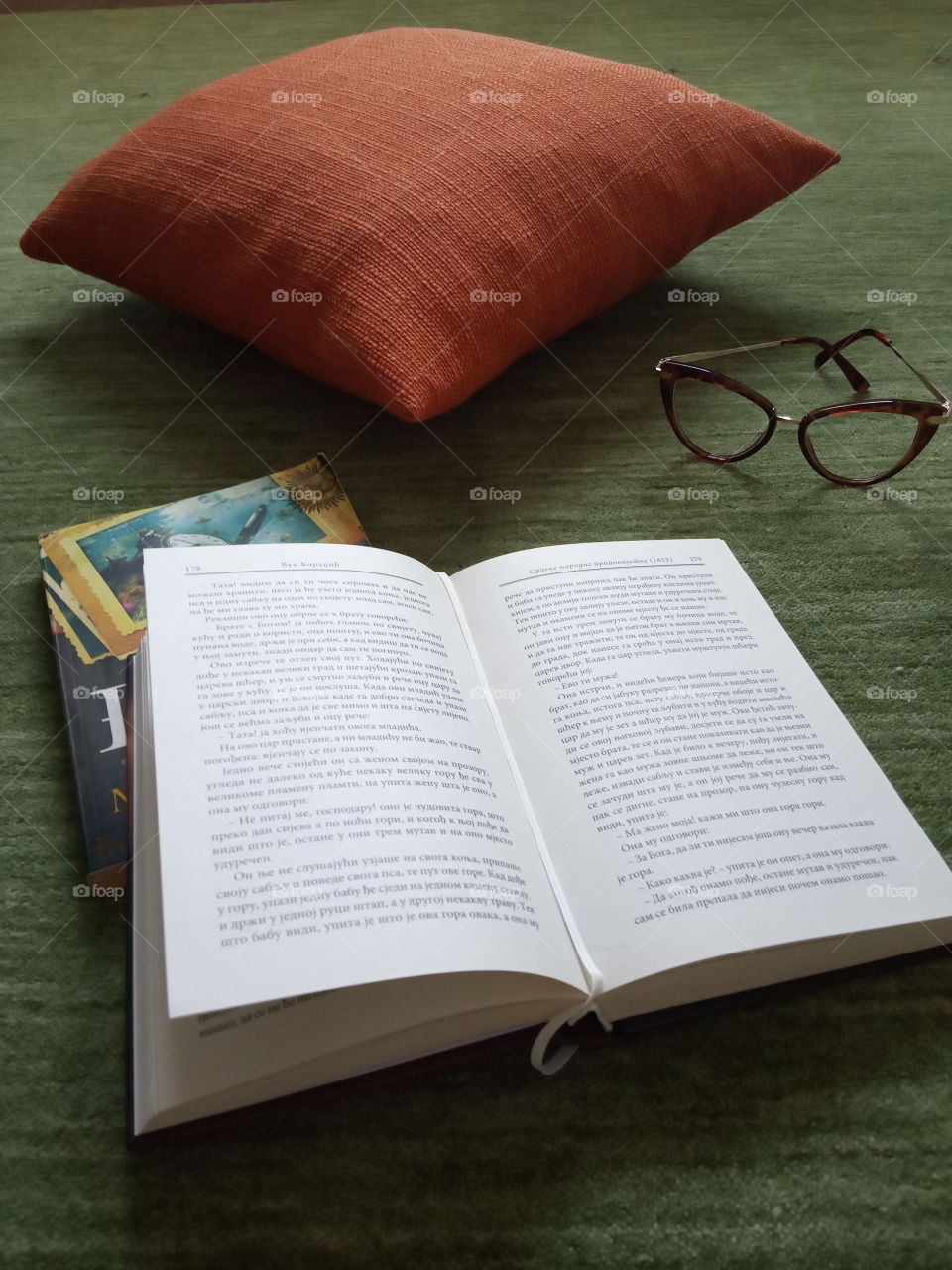 Promotion of book reading, arrangement of orange pillow, books and glasses.