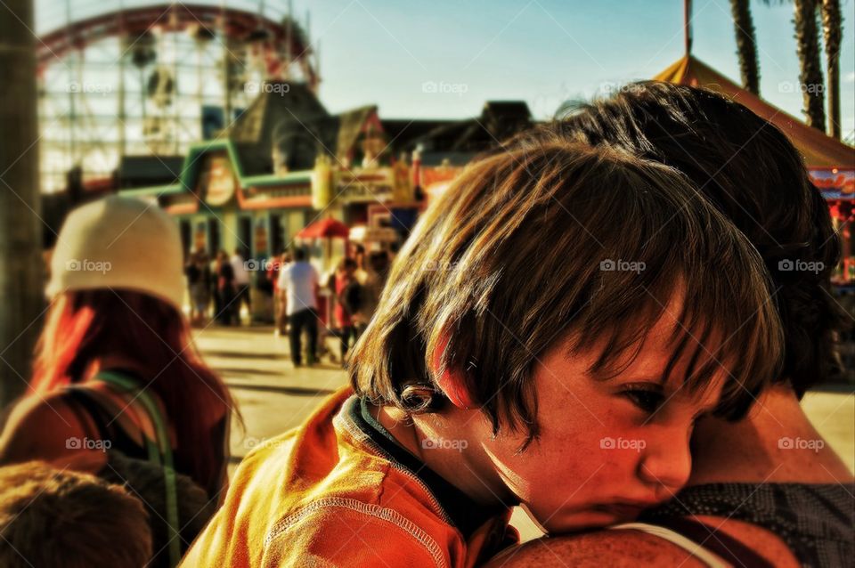 Young boy falling asleep on the shoulder of his mother