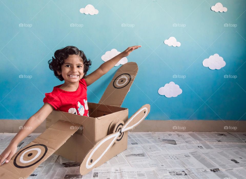 Kid playing in diy carton box aeroplane.