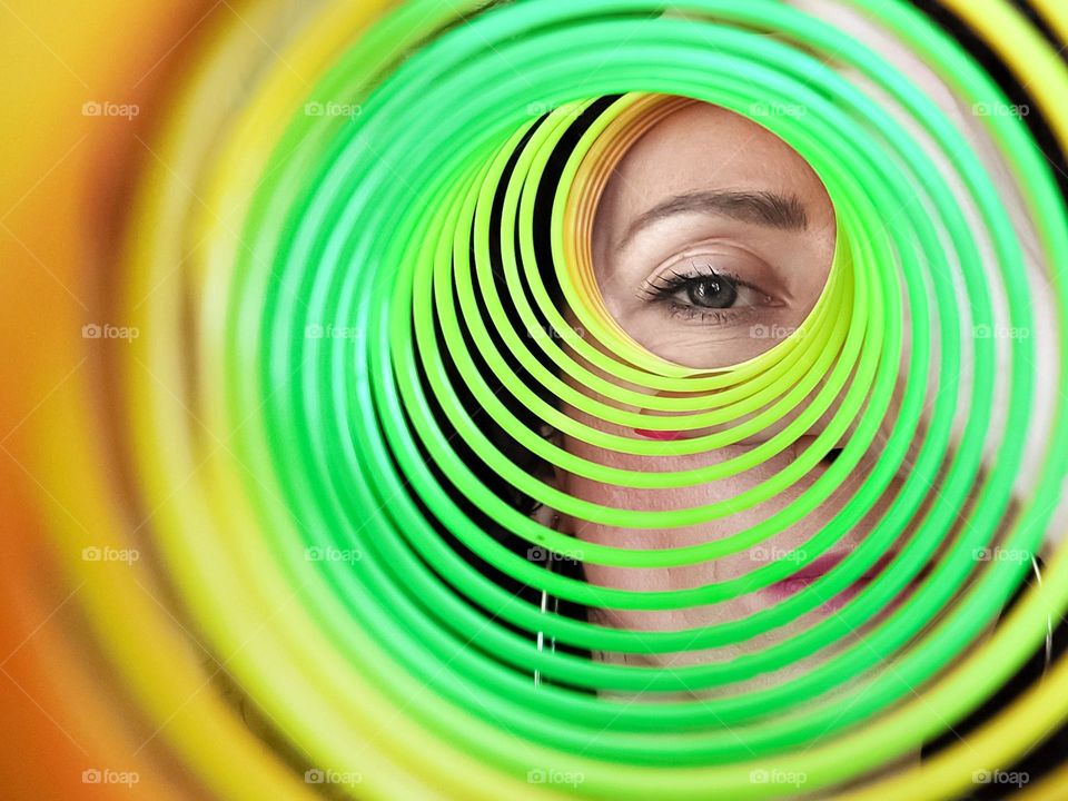 Circle, A Woman Looks through Rainbow Spring Toy