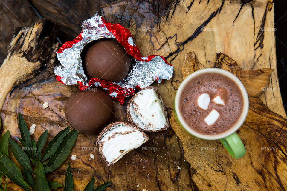 The first autumn signs when you want to still spend time outdoors but with hot chocolate and comfort food! Image of hot chocolate and marshmallow chocolates on wood.